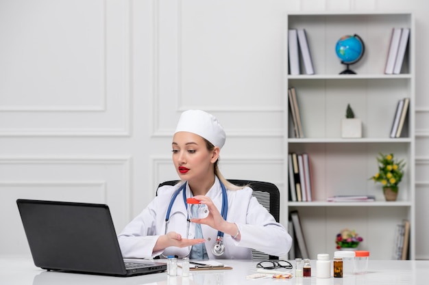 Medische mooie schattige dokter in witte ziekenhuisjas en hoed met computer die een pot vasthoudt