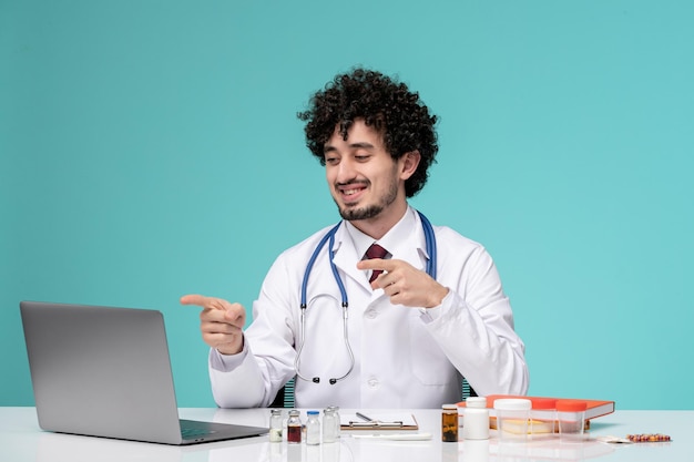 Medische schattige knappe dokter die op afstand aan de computer werkt in laboratoriumjas blij op de camera