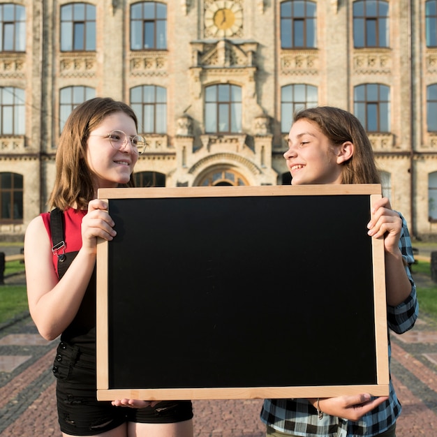 Medium geschoten middelbare schoolmeisjes die bord houden