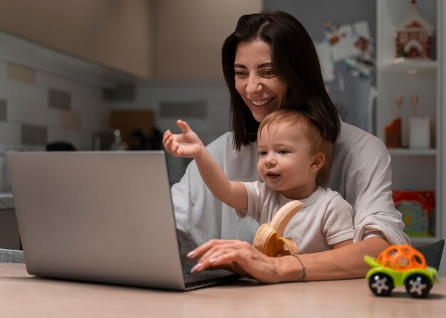 Medium geschoten moeder aan het werk en baby vast te houden