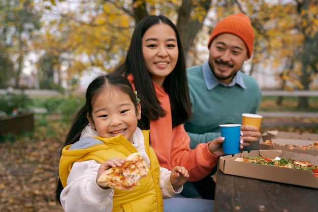 Medium geschoten ouders en kind die buiten pizza eten