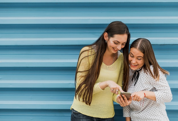 Medium geschotene smileymeisjes die smartphone bekijken