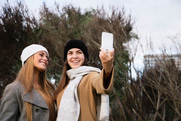 Medium schoot twee glimlachende vrouwen die een selfie nemen