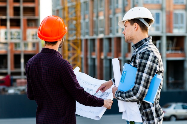 Gratis foto medium shot achteraanzicht van ingenieur en architect toezicht op de bouw