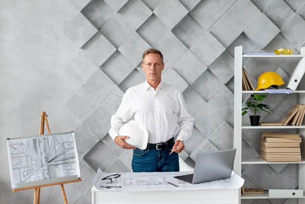 Medium shot architect die zich voordeed op zijn kantoor