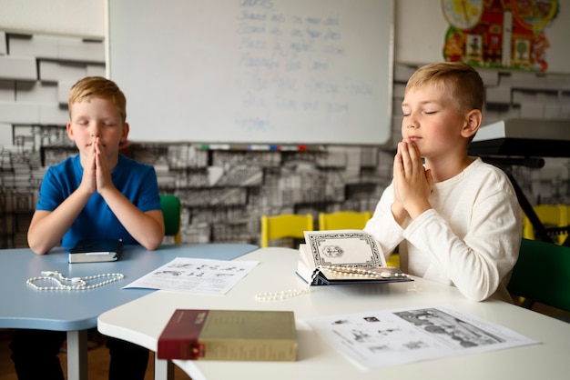 Medium shot kinderen bidden op zondagsschool