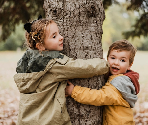 Gratis foto medium shot kinderen knuffelen boom