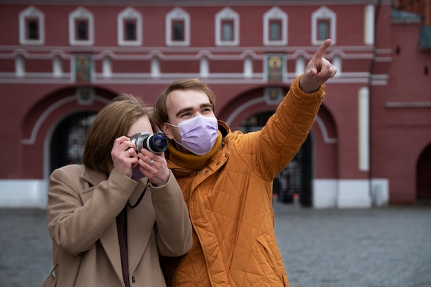 Gratis foto medium shot koppel met maskers die foto's maken