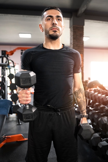 Medium shot man aan het trainen met dumbbells