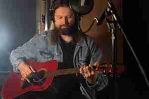 Gratis foto medium shot man die gitaar speelt in de studio