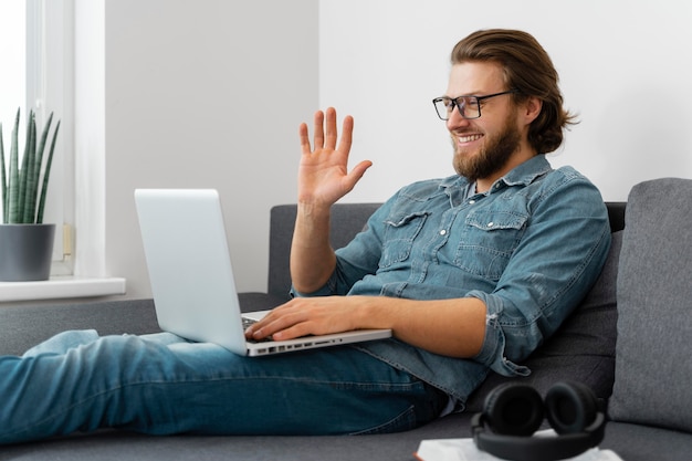 Medium shot man zwaaien naar laptop