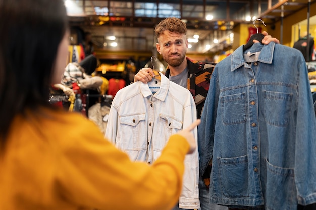 Gratis foto medium shot mensen kijken naar kleding in kringloopwinkel