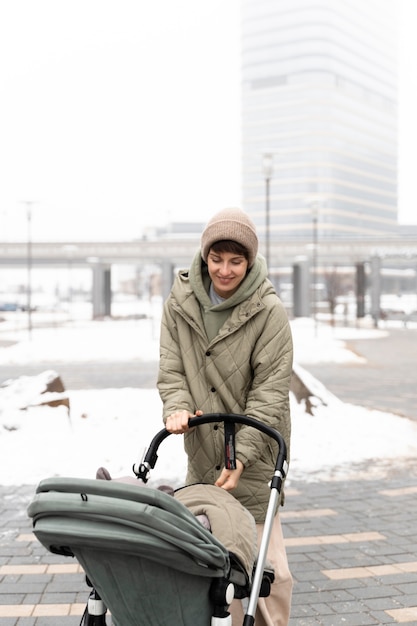 Gratis foto medium shot moeder wandelen met kinderwagen