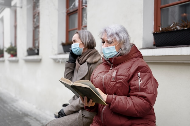 Gratis foto medium shot oude vrouw die buiten aan het lezen is