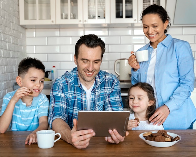 Medium shot ouders en kinderen met tablet