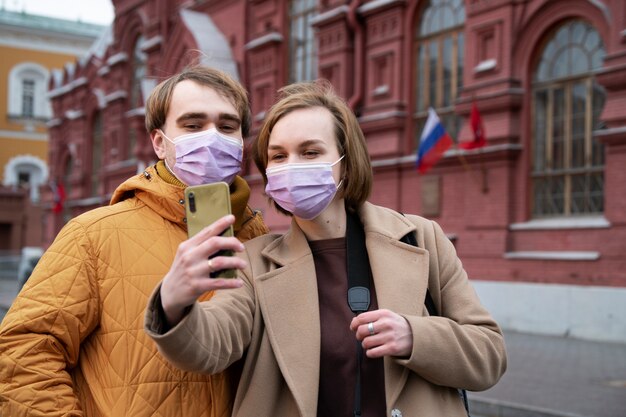 Medium shot paar met gezichtsmaskers die selfie nemen