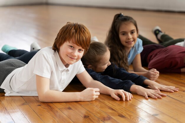 Medium shot smiley kinderen die op de vloer liggen