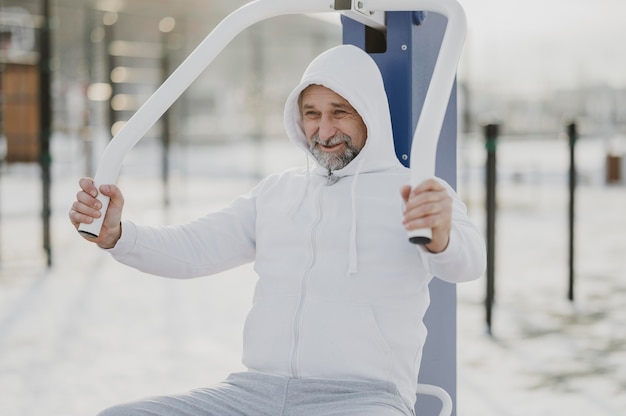 Gratis foto medium shot smiley-man die buiten traint