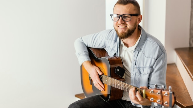 Medium shot smiley man gitaar spelen