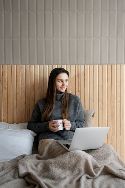 Medium shot smiley vrouw in bed met laptop