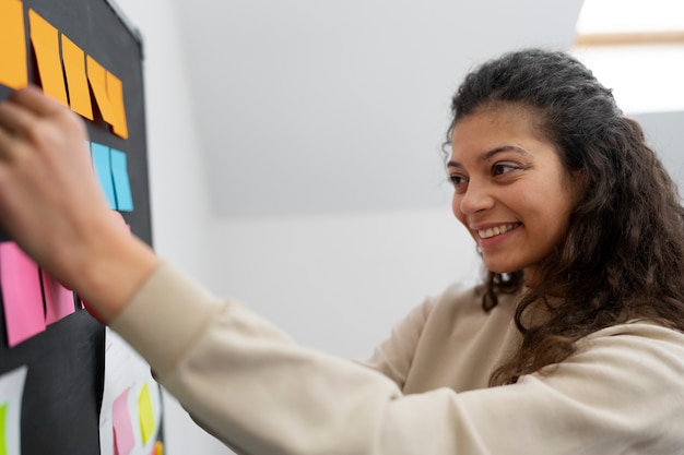 Gratis foto medium shot smiley vrouw plakt post-it aan boord