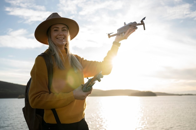 Medium shot smileyvrouw die drone buiten vasthoudt