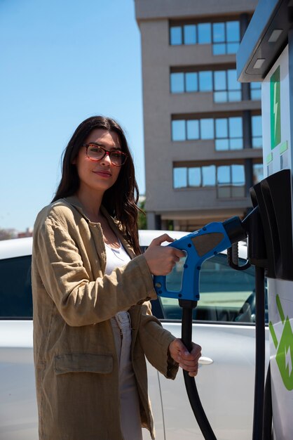 Medium shot smileyvrouw die elektrische auto oplaadt