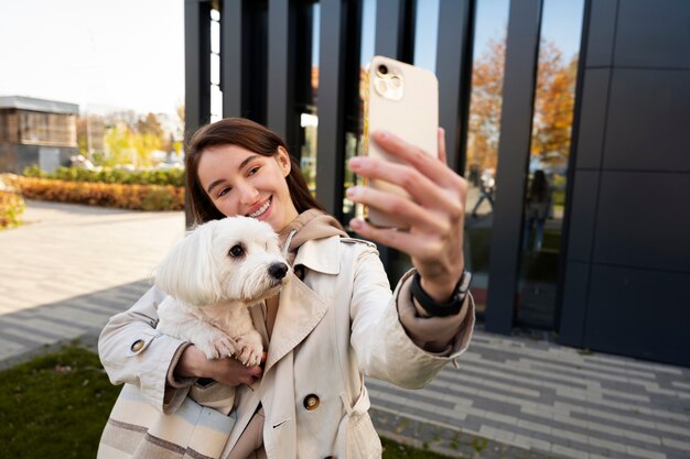 Medium shot smileyvrouw die selfie met hond neemt