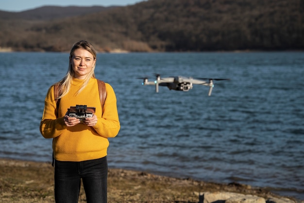 Gratis foto medium shot smileyvrouw met drone buitenshuis