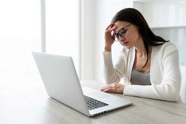 Medium shot vermoeide vrouw die met laptop werkt