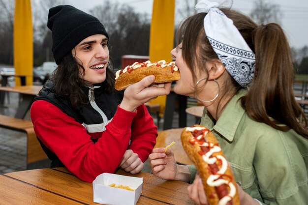 Medium shot vrienden die op een grappige manier fastfood eten