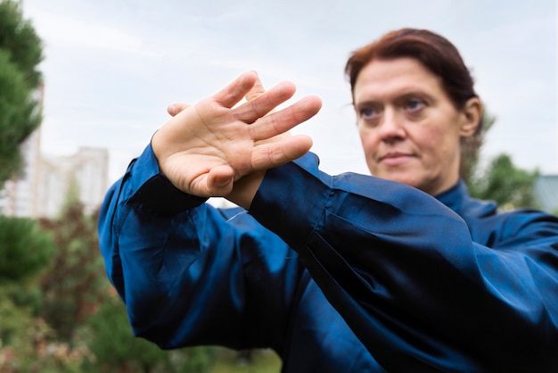 Gratis foto medium shot vrouw die buiten tai chi beoefent