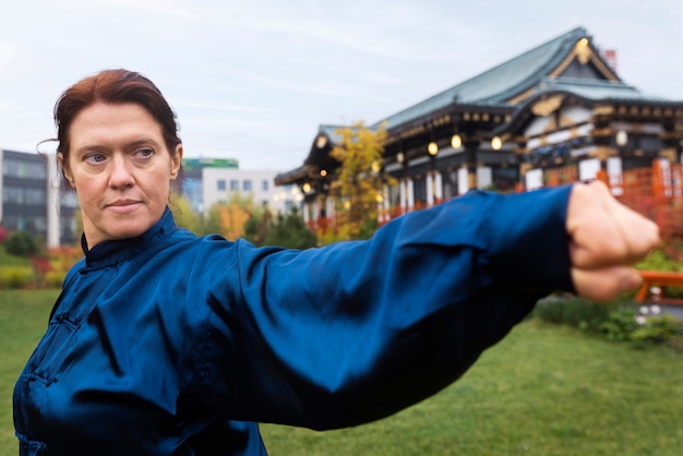 Medium shot vrouw die buiten tai chi beoefent