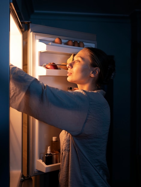 Medium shot vrouw die in de koelkast kijkt