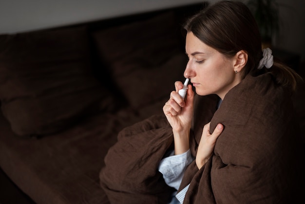 Medium shot vrouw die neusspray gebruikt