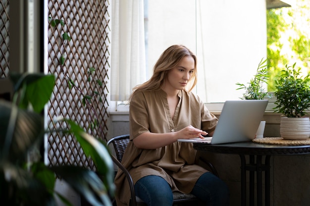 Medium shot vrouw die op laptop aan tafel werkt