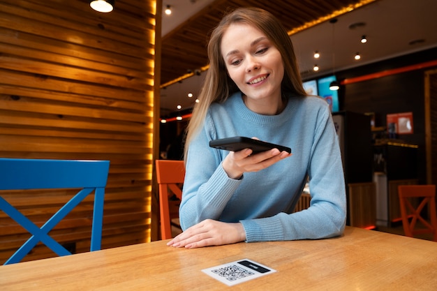 Medium shot vrouw die qr scant in restaurant