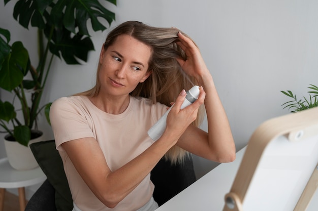 Gratis foto medium shot vrouw die thuis droge shampoo gebruikt