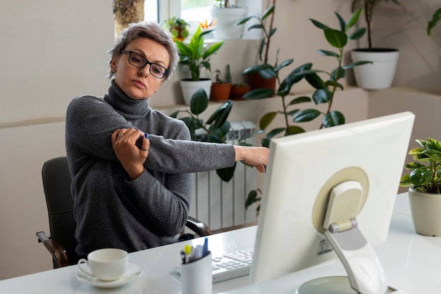 Medium shot vrouw die zich uitstrekt aan het bureau