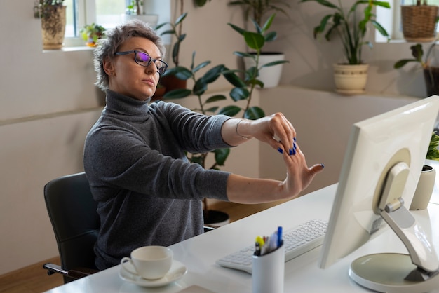 Medium shot vrouw die zich uitstrekt aan het bureau