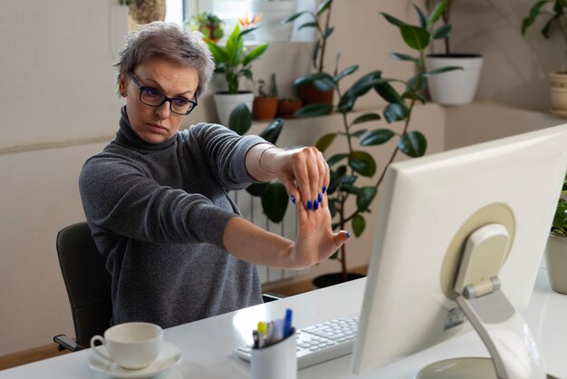 Medium shot vrouw die zich uitstrekt aan het bureau