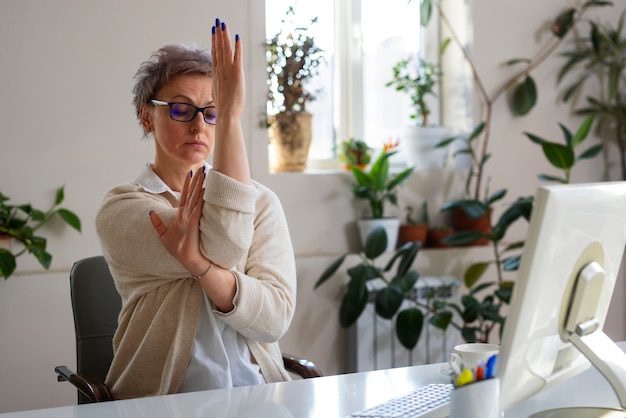 Gratis foto medium shot vrouw die zich uitstrekt aan het bureau