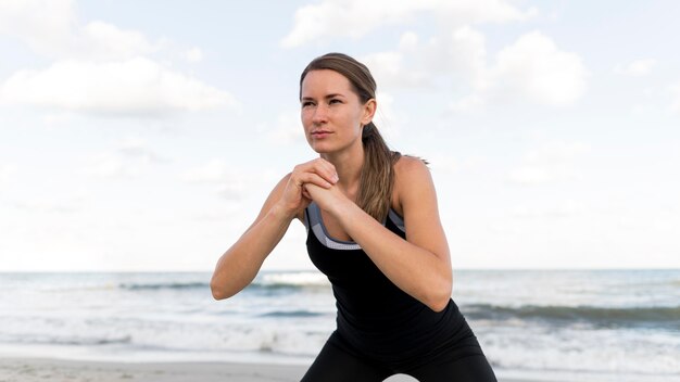 Medium shot vrouw die zich uitstrekt op het strand