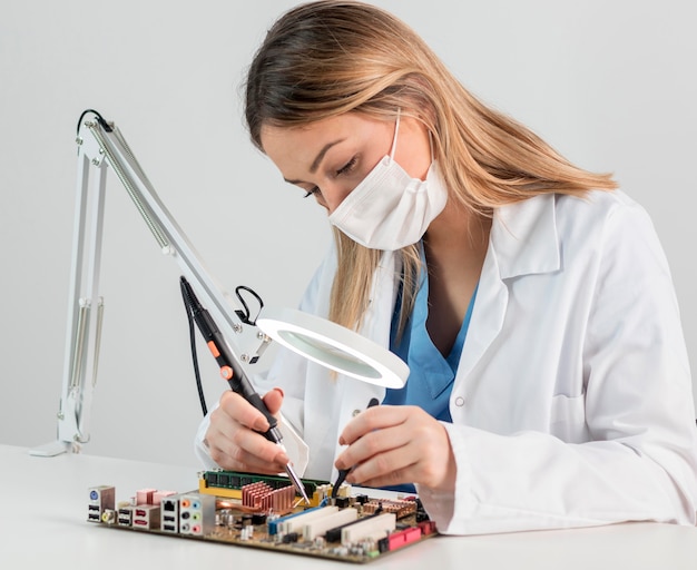 Medium shot vrouw met gezichtsmasker aan het werk