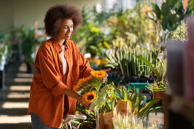 Gratis foto medium shot vrouw met prachtige zonnebloemen