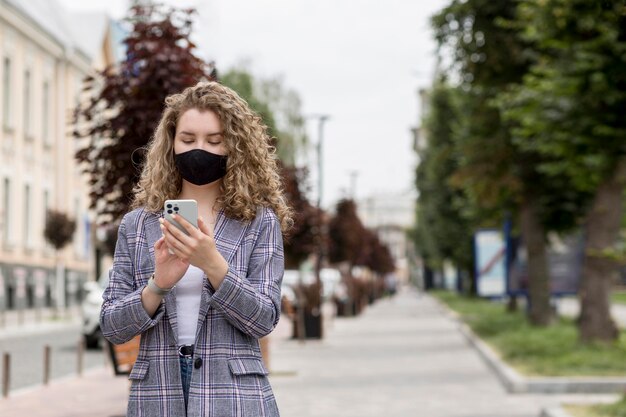 Medium shot vrouw met telefoon buitenshuis