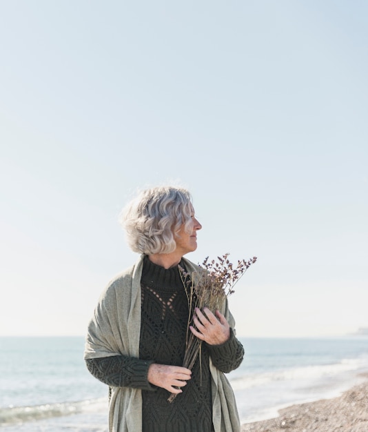 Gratis foto medium shot vrouw op het strand met bloemen