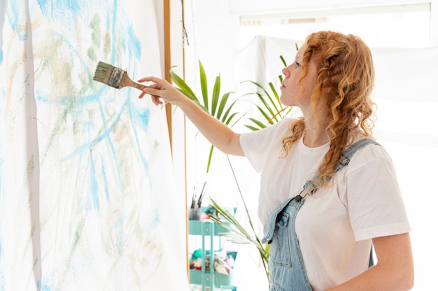 Gratis foto medium shot vrouw schilderij aan de muur