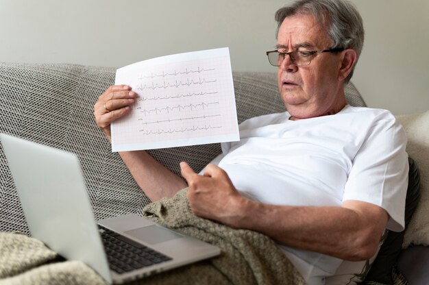 Medium shot zieke man op bank met laptop