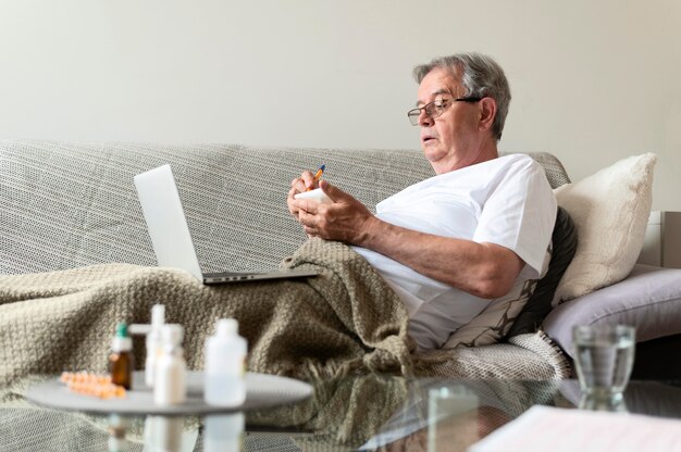 Medium shot zieke man zittend op de bank